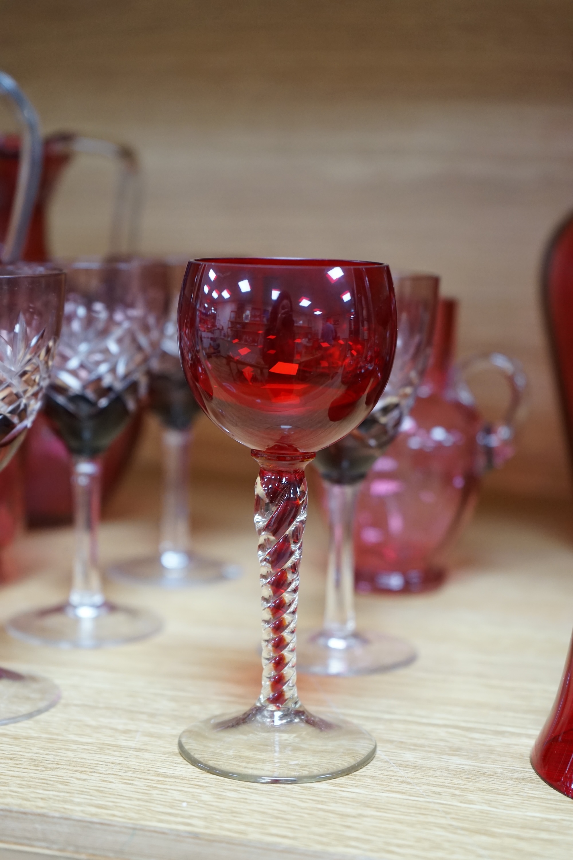 Mixed cranberry glassware to include jugs, glasses, jars and a comport, largest 23cm high. Condition - fair to good